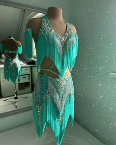 a mannequin dressed in turquoise and silver with sequins on it's sides