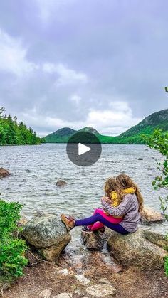 two people sitting on rocks near the water