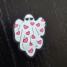 a white sticker with pink and red hearts in the shape of a ghost on a black surface