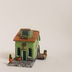 a small green house sitting on top of a white table