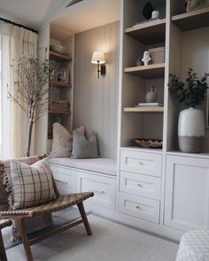 a living room filled with white furniture and lots of shelves next to a large window