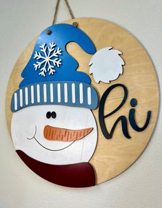 a wooden sign with a snowman's hat and name hanging on the wall