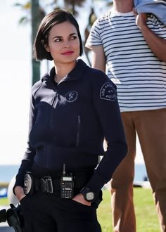 a woman in police uniform standing next to a man with a camera on her shoulder