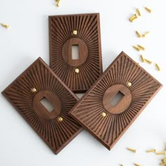 three decorative wooden pieces with holes in the middle and gold rivets around them