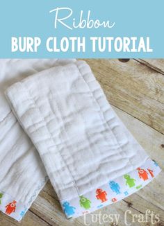 two baby burp cloths sitting on top of a wooden floor next to each other