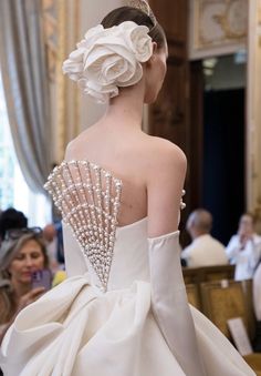 the back of a woman's wedding dress with pearls on it