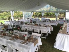 tables and chairs are set up in a tent for an outdoor wedding or party with white linens