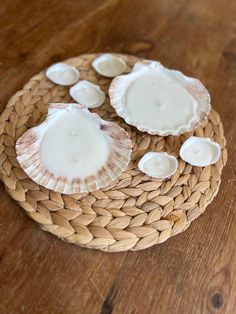 three seashells sitting on top of a wicker basket filled with white candles