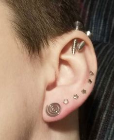 a person with ear piercings on their ears and behind the ear is a spiral design