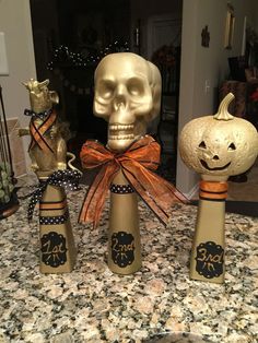 three wine bottles decorated to look like pumpkins with faces on them and bows tied around the tops