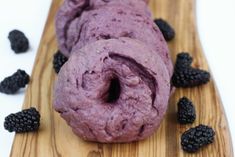 a purple doughnut on a wooden board with blackberries