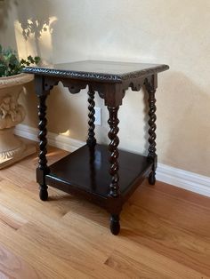 a wooden table sitting on top of a hard wood floor next to a potted plant