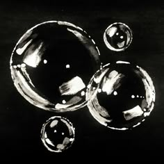 black and white photograph of three bubbles floating in the air on a dark background,