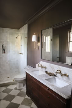 a bathroom with two sinks, a toilet and a walk in shower area next to a checkered tile floor