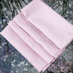 two folded pink napkins sitting on top of a flowery tablecloth covered in white flowers