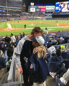 a man and woman are kissing in the stands at a baseball game as fans look on