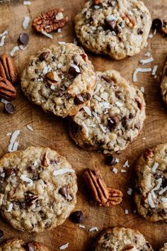 chocolate chip cookies with pecans and coconut flakes on a wooden cutting board surrounded by pecans