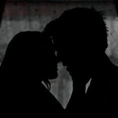 the silhouette of two people kissing in front of a window