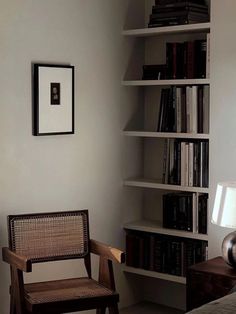 a chair sitting in front of a bookshelf filled with lots of books next to a lamp