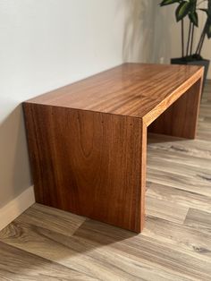 a wooden bench sitting on top of a hard wood floor next to a planter