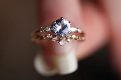 a woman's hand holding a ring with an oval blue stone in the middle