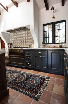 a large kitchen with black cabinets and an area rug on the floor in front of it