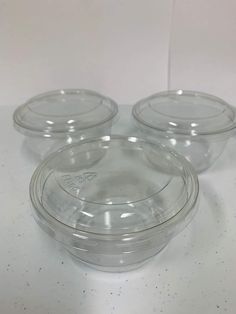 three clear plastic bowls with lids on a white table