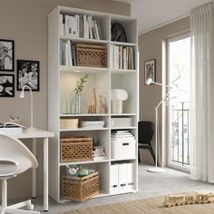 a white bookcase filled with lots of books next to a desk and chair in front of a window