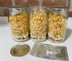 three glass jars filled with pasta sitting on top of a counter