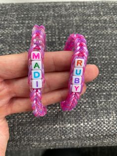 a person holding two pink and white beads with the words mad ruby spelled on them