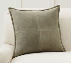 a white couch with a green pillow on it's back and two pillows sitting next to each other