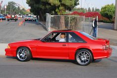 a red sports car is parked on the side of the road with people in it