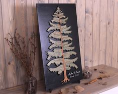 a wooden christmas tree sitting on top of a mantle next to a vase with dried flowers