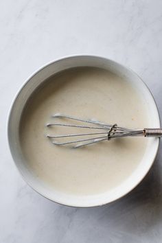 a bowl filled with cream and whisks on top of a white countertop