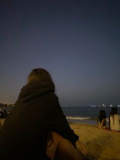 people are sitting on the beach at night