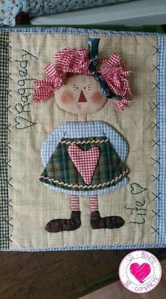 a quilted wall hanging with a doll on it