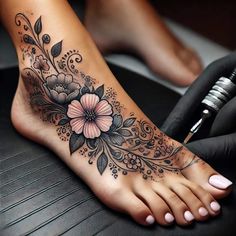 a woman's foot with flowers and leaves on the top part of it, while she is getting her tattoo done