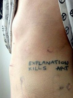 the word explanation kills art is written on someone's lower back and upper arm