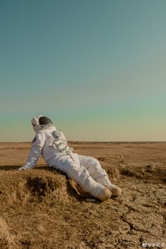 an astronaut is laying on the ground with his feet in the air and wearing white spacesuits