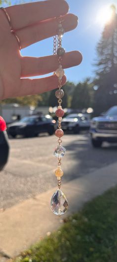 a person holding onto a long chain with beads and stones hanging from it's end