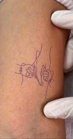 a person in white gloves holding up a tattoo