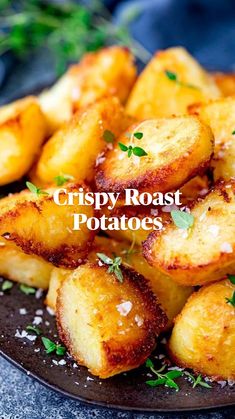 fried potatoes with parmesan cheese and herbs on a black plate, ready to be eaten