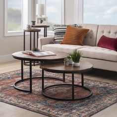 two tables sitting on top of a rug in front of a couch and table with a potted plant