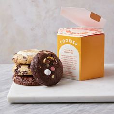 three cookies are on a white plate next to a carton of cookie's