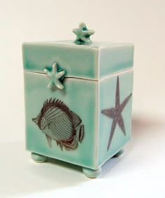 a small blue box with a fish and starfish on the lid sitting on a white surface