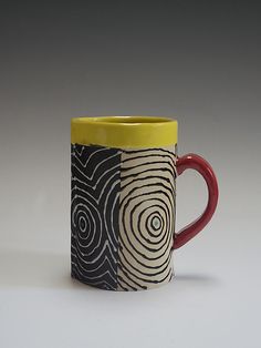 a coffee cup with yellow rim and black swirl design on the inside, sitting on a white surface