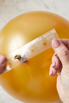 a person holding a balloon with a ticket attached to it's side, in front of a marble background