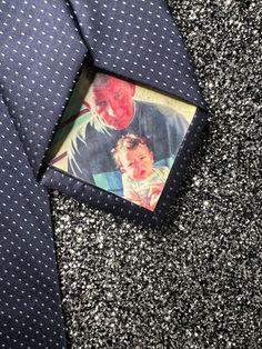 a blue tie with a picture of two men on it and a black speckled background