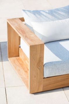 a wooden bench sitting on top of a tile floor next to a white and blue pillow