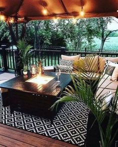 an outdoor living area with couches, tables and lamps on the deck overlooking trees